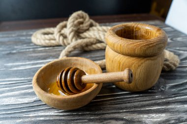 Bal-dipper 'dan damlayan aromatik bal. Kasedeki bal. Ahşap arka planda tahta kaplamalardan bal damlıyor. Seçici odak.