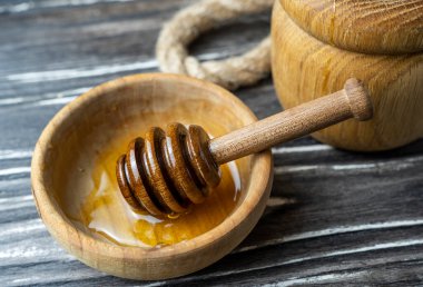 Bal-dipper 'dan damlayan aromatik bal. Kasedeki bal. Ahşap arka planda tahta kaplamalardan bal damlıyor. Seçici odak.