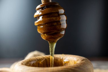 Bal-dipper 'dan damlayan aromatik bal. Kasedeki bal. Ahşap arka planda tahta kaplamalardan bal damlıyor. Seçici odak.