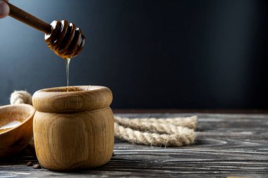 Bal-dipper 'dan damlayan aromatik bal. Kasedeki bal. Ahşap arka planda tahta kaplamalardan bal damlıyor. Seçici odak.