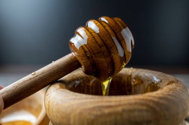 Bal-dipper 'dan damlayan aromatik bal. Kasedeki bal. Ahşap arka planda tahta kaplamalardan bal damlıyor. Seçici odak.