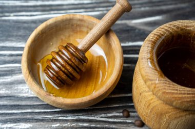 Bal-dipper 'dan damlayan aromatik bal. Kasedeki bal. Ahşap arka planda tahta kaplamalardan bal damlıyor. Seçici odak.