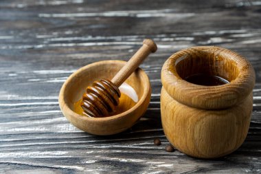 Bal-dipper 'dan damlayan aromatik bal. Kasedeki bal. Ahşap arka planda tahta kaplamalardan bal damlıyor. Seçici odak.