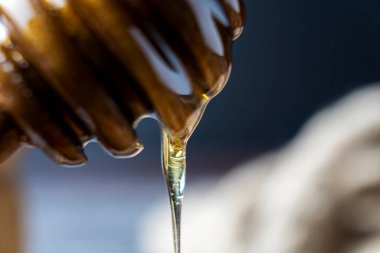 Bal-dipper 'dan damlayan aromatik bal. Kasedeki bal. Ahşap arka planda tahta kaplamalardan bal damlıyor. Seçici odak.