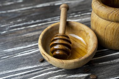 Bal-dipper 'dan damlayan aromatik bal. Kasedeki bal. Ahşap arka planda tahta kaplamalardan bal damlıyor. Seçici odak.