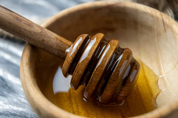 Bal-dipper 'dan damlayan aromatik bal. Kasedeki bal. Ahşap arka planda tahta kaplamalardan bal damlıyor. Seçici odak.