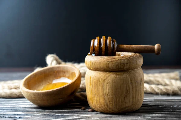 Bal-dipper 'dan damlayan aromatik bal. Kasedeki bal. Ahşap arka planda tahta kaplamalardan bal damlıyor. Seçici odak.