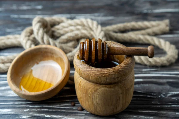 Bal-dipper 'dan damlayan aromatik bal. Kasedeki bal. Ahşap arka planda tahta kaplamalardan bal damlıyor. Seçici odak.