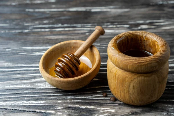 Bal-dipper 'dan damlayan aromatik bal. Kasedeki bal. Ahşap arka planda tahta kaplamalardan bal damlıyor. Seçici odak.