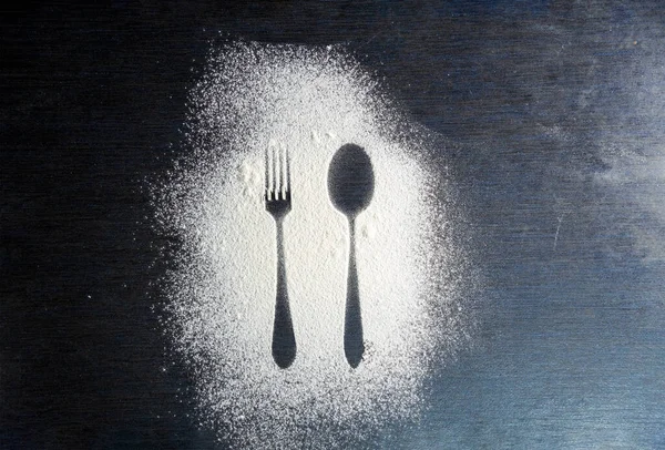 Üst kaşık ve çatal silueti koyu arkaplanda un ile yapılmış. Çatal ve kaşık silueti beyaz un üzerinde. Kırsal zıtlık arka planı. Yemek hazırlama süreci. Fırın kavramı.