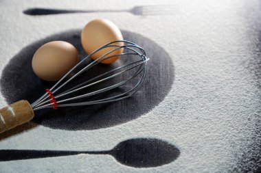 Üst kaşık ve çatal silueti koyu arkaplanda un ve yumurta ile yapılmış. Yumurta ve çırpılmış beyaz un. Kırsal zıtlık arka planı. Yemek hazırlama süreci. Fırın kavramı.