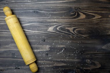 Koyu ahşap masa üzerinde unlu raptiyeler, üst görüş, metnin için bedava fotokopi alanı, meru, tarif. Çiğ hamuru tahta oklavayla düzleştirdim. Pişirme arkaplanı.