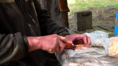 Orta yaşlı erkek avcının ekmek ve etle yemek yaptığı görüntüler.