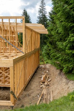 Dağ ormanındaki ahşap ev inşaatının manzaralı görüntüsü.