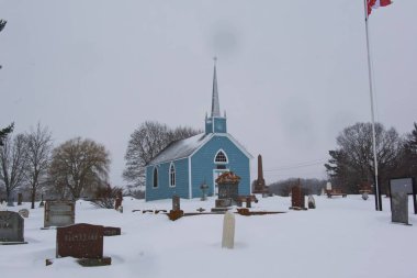 Mavi bir kilise ve kışın bir mezarlık