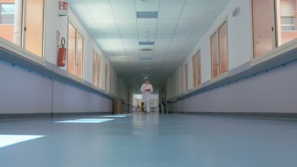 Egy fehér egyenruhás orvos sétál a folyosón. — Stock videók
