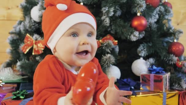 サンタクロースのスーツの子供はクリスマスツリーの近くで遊ぶ. — ストック動画