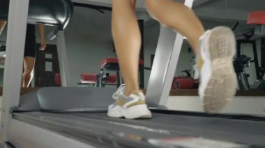 Genç atletik kadın koşu bandında koşuyor..