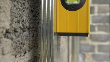 Sıvı denge cetveli. Duvara metal profil çerçevesi yerleştiriliyor, dikey sapmayı ölçüyor. Kabarcık seviyesi cetveli.