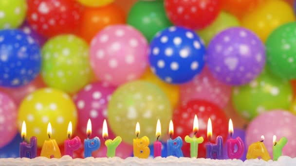 以题词的形式吹灭色彩斑斓的生日蜡烛 背景是彩色气球 祝你生日快乐 — 图库视频影像