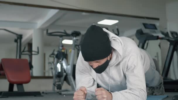 Sportman Met Een Zwarte Hoed Een Beschermend Gezichtsmasker Die Planktraining — Stockvideo