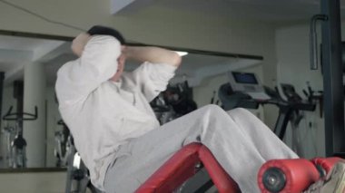Sporcu spor salonunda karın kaslarını çalıştırır. Vücut geliştirici Roma sandalyesinde karın kası egzersizi yapıyor..
