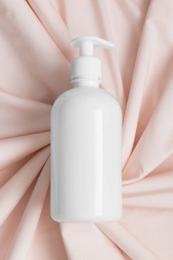 Beyaz kozmetik sıvısı sabun şişesi yumuşak pembe tekstil üzerinde maket..