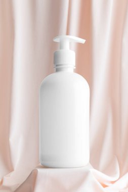 Beyaz kozmetik sıvısı sabun şişesi yumuşak pembe tekstil üzerinde maket..