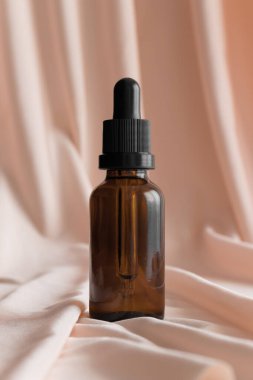 Damla şişesi yumuşak pembe tekstil üzerinde..