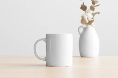 Tahta masa üzerinde okaliptüs süslemesi olan beyaz kupa modeli..