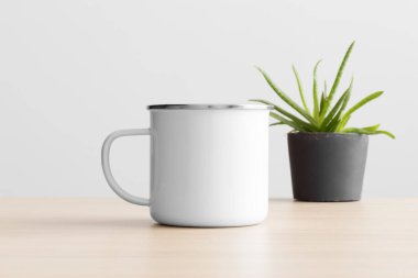 Ahşap masanın üzerinde aloe vera bitkisi olan Enamel kupası..