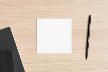 Tahta masanın üzerinde çalışma alanı aksesuarları olan kare davet kartı modeli.