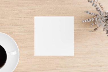 Square invitation card mockup with a lavender and a cup of coffee on the wooden table.