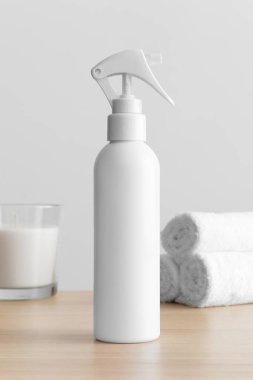 White cosmetic trigger sprayer bottle mockup with a candle and towels on the wooden table.
