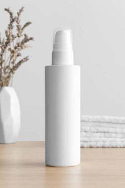 White cosmetic lotion bottle mockup with a lavender and towels on the wooden table.