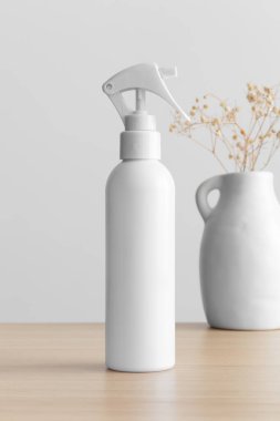 Beyaz kozmetik tetik püskürtücü şişesi ahşap masada bir çingene masası var..