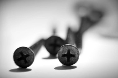 Beyaz masanın üzerinde beş vida var. Siyah ve beyaz.