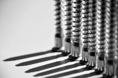 Vidalar beyaz masanın üstünde dikey olarak duruyor. Siyah ve beyaz uzun gölgeler bırakıyorlar.