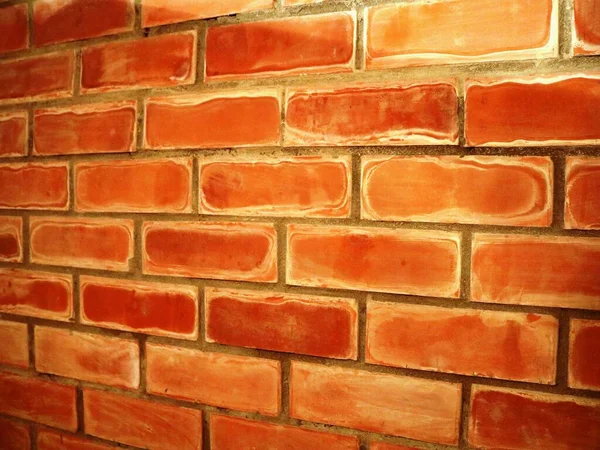 角を曲がったところにあるテラコッタのレンガの壁内部の石積みのレンガを角度でテクスチャ 明るいオレンジ色の色合いのレンガの壁のテクスチャ — ストック写真