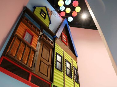 Odanın tasarımı yapısında parlak çok renkli tonlarda bir ev, odanın tavanındaki duvarda uçan bir ev, dekordaki renkli sahte bir evin modeli.