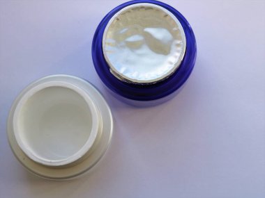 Boş yüz kremi kavanozu ve açılmamış kavanoz üst görünümü, hafif arka planda cilt bakımı için yeni krem kavanozları, kadın güzellik malzemeleri, kozmetik ürünleri