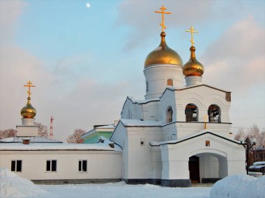 Lesnoy, Sverdlovsk bölgesi, Rusya - 4 Ocak 2022: Yaldızlı kubbeleri, haçları ve girişi üzerinde bir ikonu olan beyaz tapınak, bir kış akşamı manzarasında Rus Ortodoks kilisesi