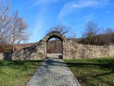 Güneşli mevsim manzarasında, kaldırım taşından duvarda güzel bir kemer, Avrupa seyahati kartpostalları, eski harabelerde yürüyüş yolları, kaya kemerine giden kaldırımlı yollar.