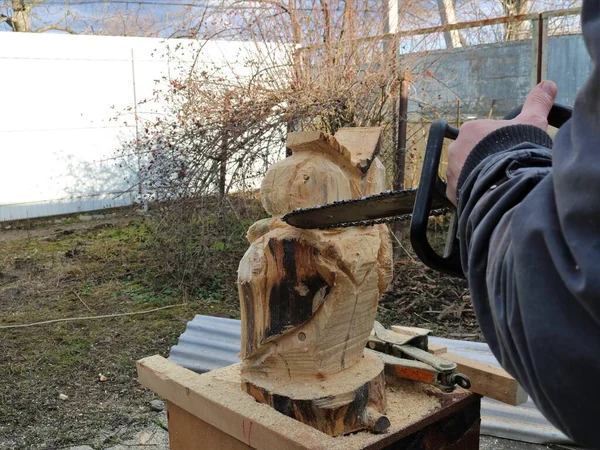 チェーンソーで木からフクロウの像を見ると 大工は通りの木片から人形を切り取り のこぎりで木製の装飾を作成します — ストック写真