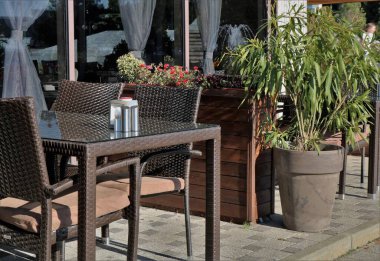 Güneşli bir günde tencerelerde hasırdan mobilyalar ve doğal çiçeklerle dolu bir sokak kafesi ya da restoranın rahat köşesi, eski tarz bistro 'nun boş açık hava masaları, insanların olmadığı restoran sahneleri.