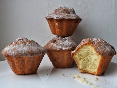 Beyaz olmayan bir tabaktaki muffinler, arkaplandaki desenli duvar, ev yapımı ya da hafif hamur işlerinden elde edilen kekler üzerine pudra şekeri serpilmiş.