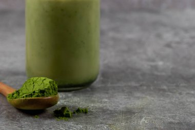 Bir kepçe kibrit yeşil çay tozu ve arkasında da kibrit latte.