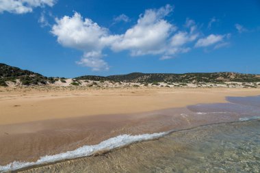 Kuzey Kıbrıs 'taki Karpas Yarımadası boyunca uzanan Golden Beach' teki okyanus kum tepelerine bakıyorum.