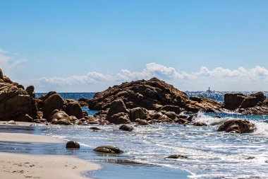 Looking out over the rocky coastline from Porth Nanven beach in Cornwall, with a distant view of Longships lighthouse off Land's End