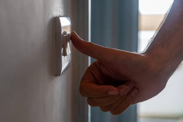 A man turning off a light switch, with a shallow depth of field